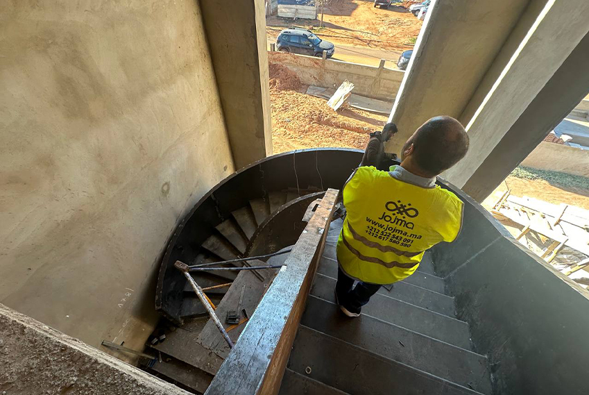 Technicien JOJMA installant un escalier hélicoïdal métallique sur mesure sur un chantier au Maroc