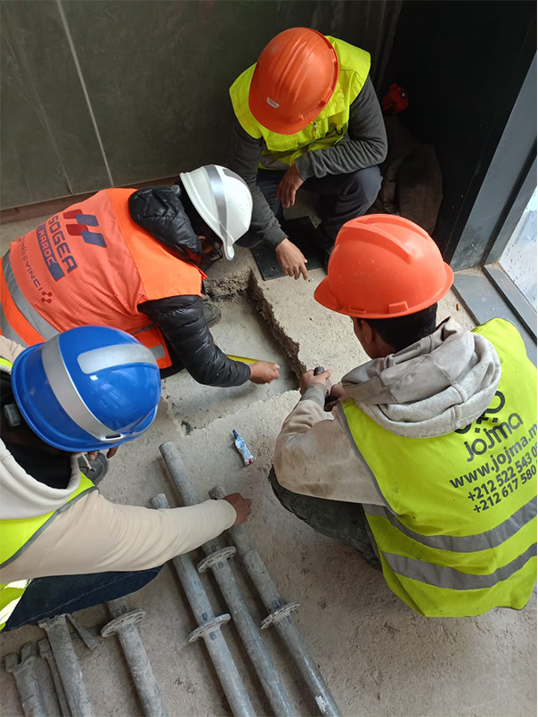 Techniciens réalisant les travaux d’ancrage au sol d’un escalier hélicoïdal métallique