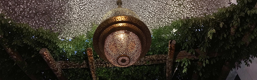Luminaire décoratif en métal travaillé artisanalement dans un espace architectural au Maroc.