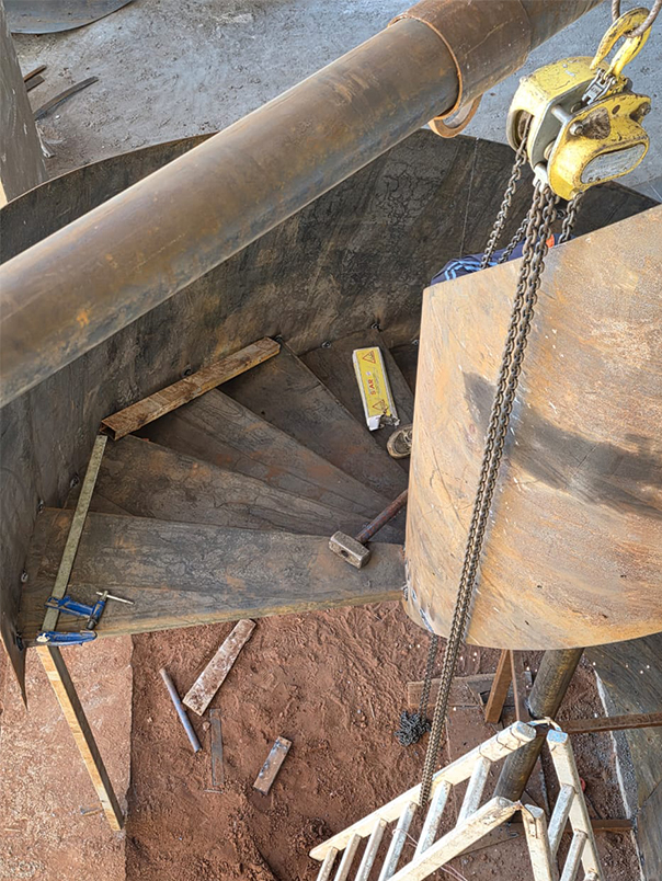 Détail de montage des marches métalliques et de l’enveloppe courbe d’un escalier hélicoïdal
