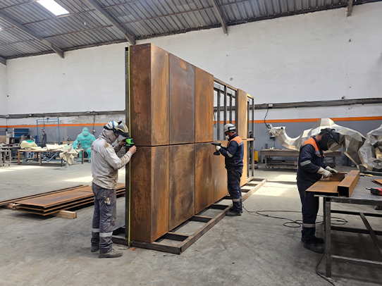 Équipe JOJMA réalisant l’assemblage et le contrôle de panneaux métalliques sur mesure dans son atelier au Maroc.