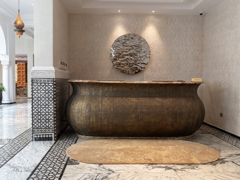 Comptoir d’accueil sur mesure en métal à finition bronze dans un intérieur haut de gamme d’inspiration marocaine