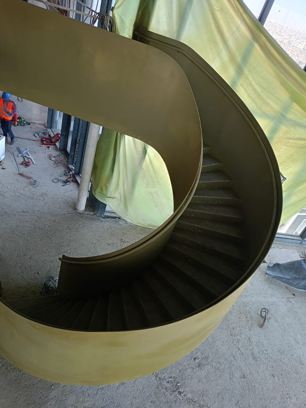 Vue plongeante d’un escalier hélicoïdal métallique avec marches courbes et enveloppe extérieure continue