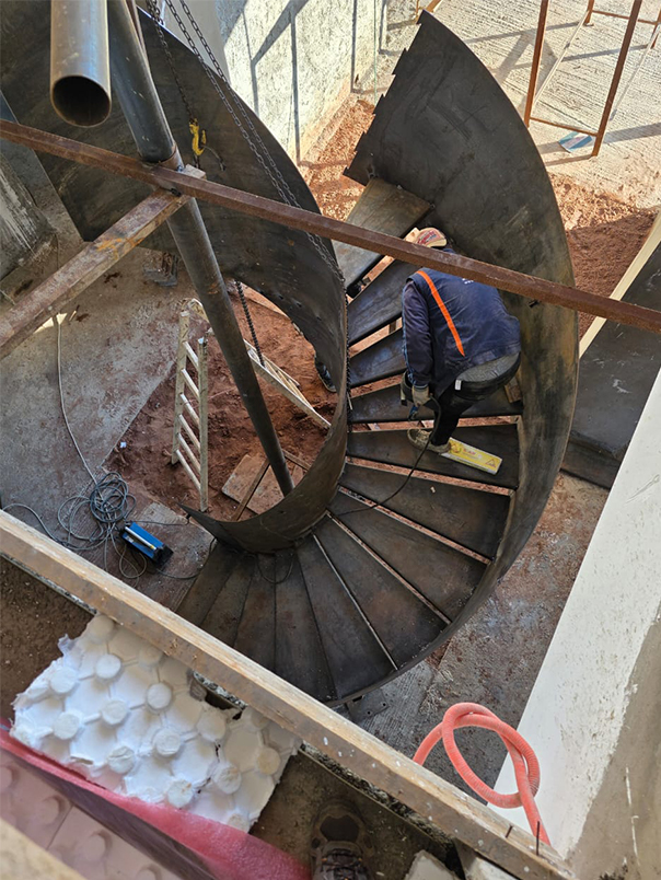 Vue plongeante sur les marches métalliques d’un escalier hélicoïdal en cours d’assemblage