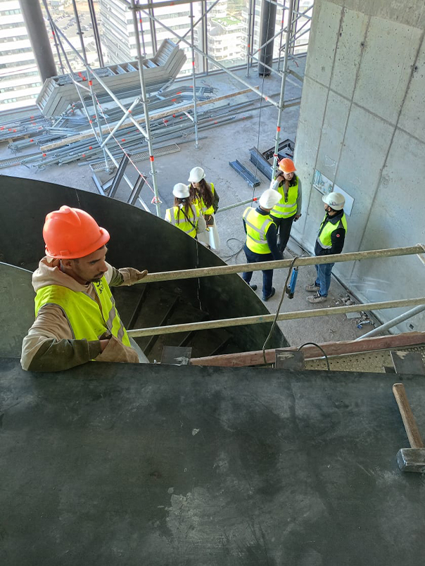 Équipe technique sur chantier autour d’un escalier hélicoïdal métallique en cours d’installation dans la Tour Mohammed VI