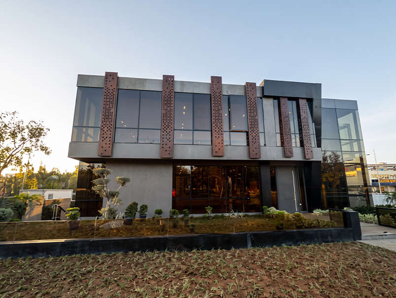 Façade contemporaine avec panneaux verticaux perforés en acier Corten intégrés devant de grandes surfaces vitrées