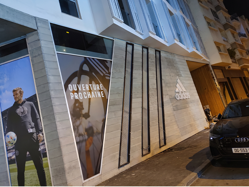 Façade commerciale Adidas avec cadres et éléments verticaux en acier Corten intégrés aux vitrines