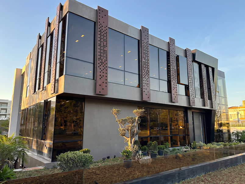 Bâtiment contemporain avec panneaux Corten perforés, grandes baies vitrées et aménagement paysager extérieur
