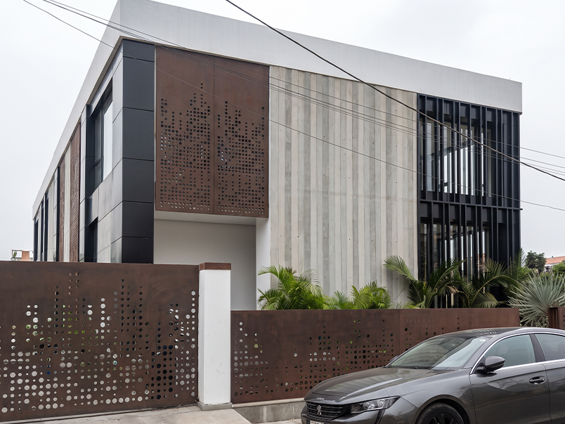 Vue générale du siège Anfa Realties avec panneaux Corten perforés, béton et éléments métalliques noirs