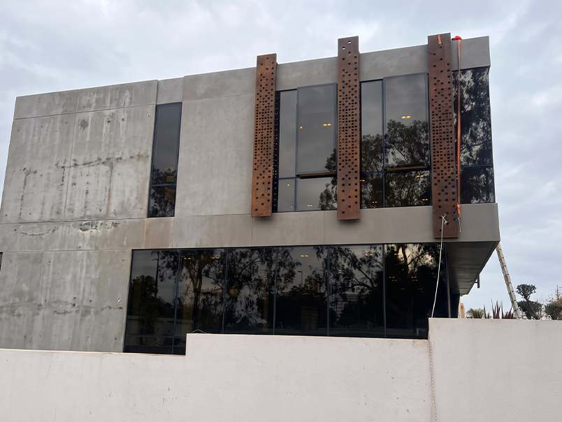 Façade latérale d’un bâtiment contemporain habillée de panneaux verticaux perforés en acier Corten