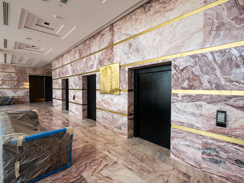 Hall d’ascenseurs haut de gamme avec revêtement mural en marbre veiné et inserts décoratifs en laiton