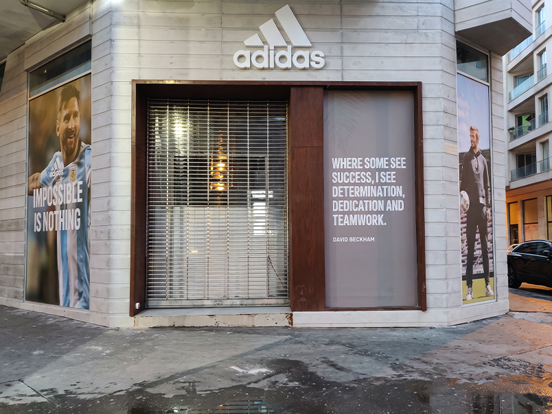 Vitrine Adidas encadrée par un habillage métallique en acier Corten sur une façade commerciale contemporaine