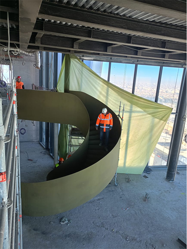Technicien sur un escalier hélicoïdal métallique monumental en cours d’installation dans la Tour Mohammed VI