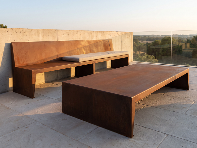 Banc et table basse en acier Corten sur une terrasse contemporaine avec garde-corps vitré