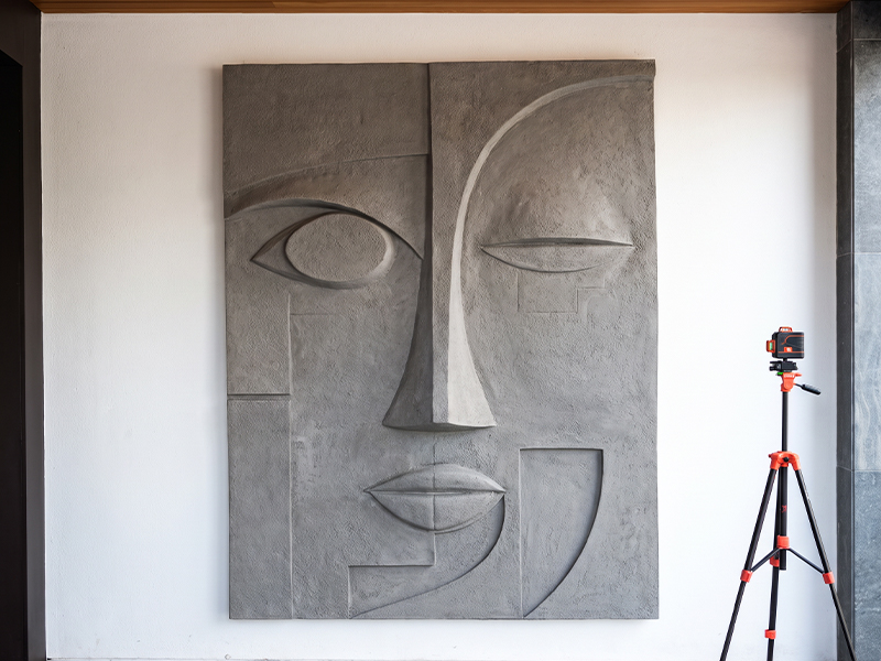 Œuvre murale en relief représentant un visage abstrait aux formes géométriques dans un intérieur contemporain
