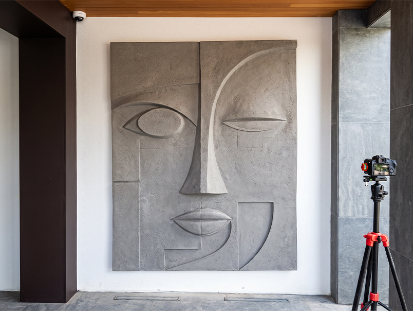 Œuvre murale monumentale en relief représentant un visage abstrait géométrique installée dans un intérieur contemporain