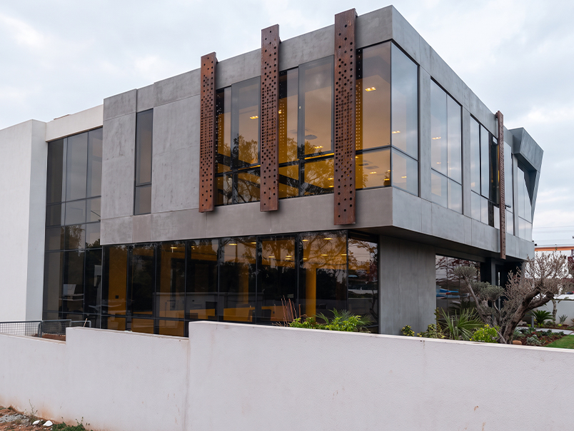 Panneaux verticaux en acier Corten perforé installés sur les façades vitrées d’un bâtiment contemporain