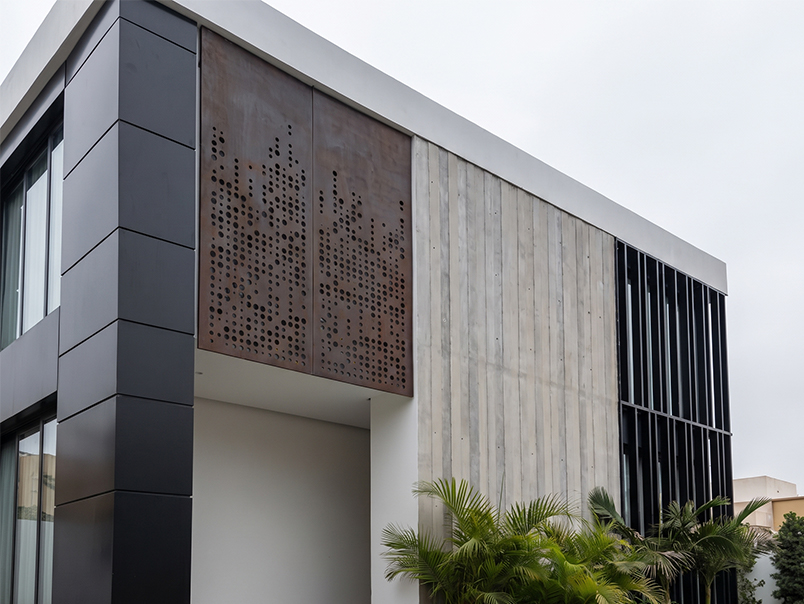 Vue générale du siège Anfa Realties avec panneaux Corten perforés, béton et éléments métalliques noirs