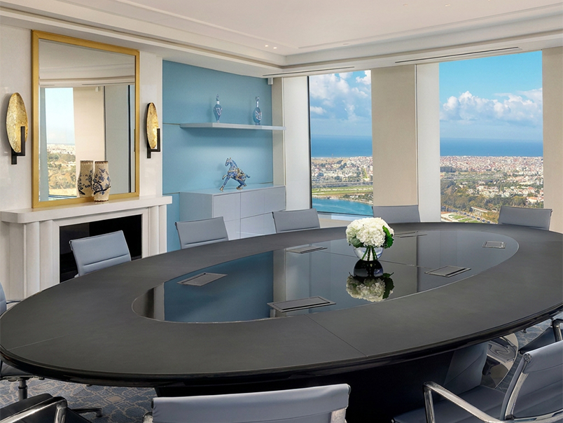 Salle de réunion contemporaine avec grande table de conférence, mobilier moderne et vue panoramique sur la ville et l’océan