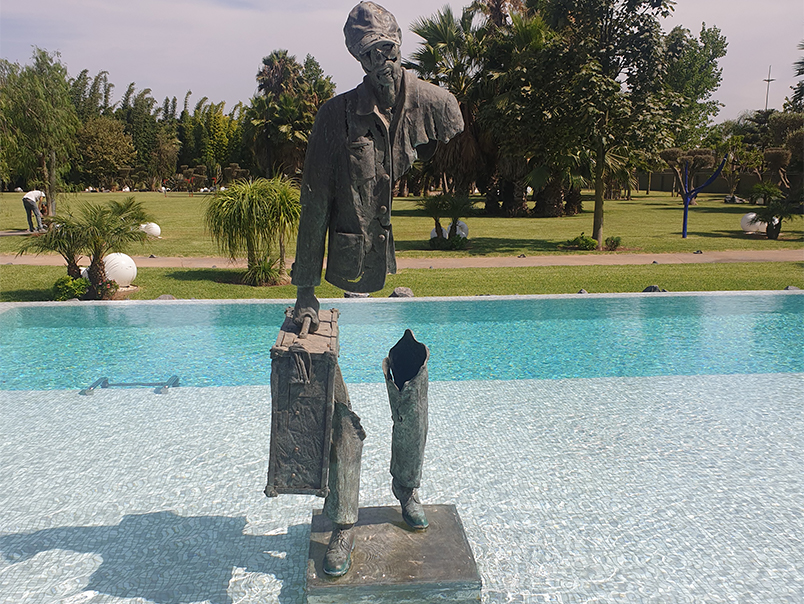 Sculpture Peigne en bronze patiné représentant un personnage fragmenté avec une valise près d’un bassin