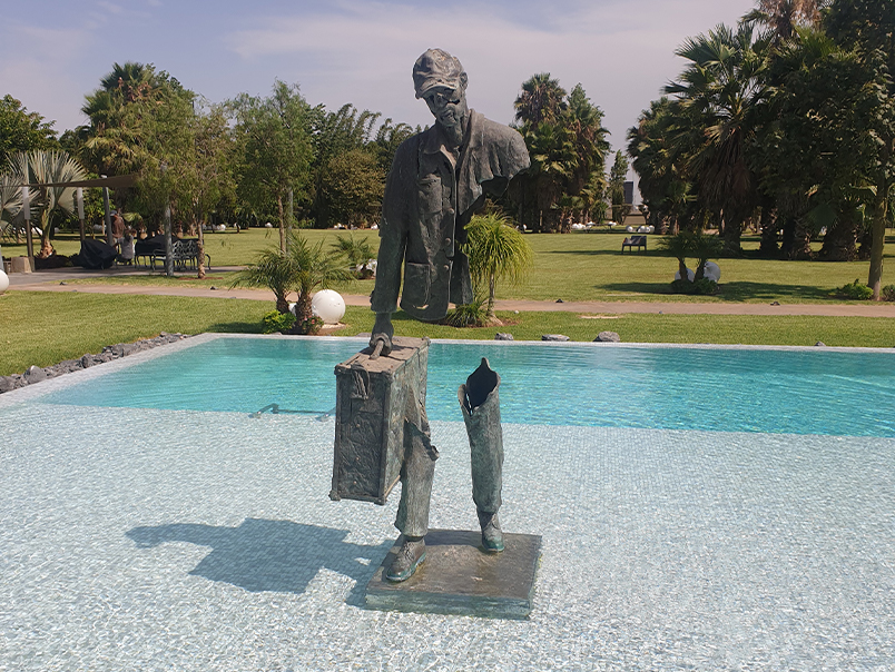 Vue complète de la Sculpture Peigne en bronze patiné installée devant un bassin dans un jardin